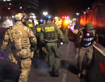 A journalist runs past federal officers after during a protest against racial injustice in front of the Mark O. Hatfield U.S. Courthouse on July 30, 2020 in Portland, Ore.