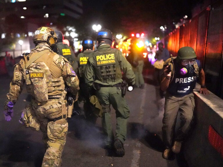 A journalist runs past federal officers after during a protest against racial injustice in front of the Mark O. Hatfield U.S. Courthouse on July 30, 2020 in Portland, Ore.