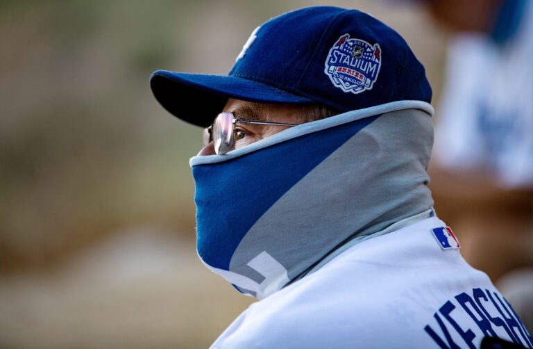 LOS ANGELES, CA - AUGUST 8, 2020: Season ticket holder David Baltazar of Long Beach wears a Dodgers neck gaiter as he sits with other fans watching the Dodgers play the San Francisco Giants from a far overlook spot because of the coronavirus pandemic in Elysian Park on August 8, 2020 in Los Angeles, CA. They are listening to the game on the radio since they are too far away to hear the sounds form the game. No fans are allowed in the stadium. (Gina Ferazzi / Los Angeles Times via Getty Images)