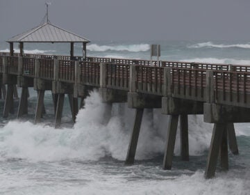 Waves crash along the Juno Beach Pier as Tropical Storm Isaias passes through the area Sunday in Juno Beach, Fla. The storm is now headed toward the Carolinas.