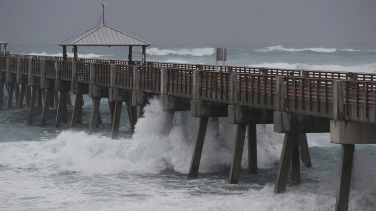 Waves crash along the Juno Beach Pier as Tropical Storm Isaias passes through the area Sunday in Juno Beach, Fla. The storm is now headed toward the Carolinas.