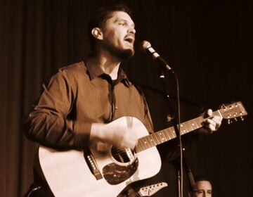 Musician John Shaughnessy singing and playing guitar