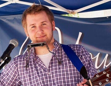 Musician Jordan Bickhart with a harmonica and guitar