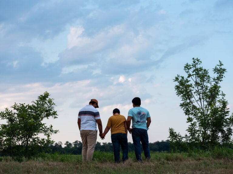 Honduran migrants, Ricardo Sr., (left), his son Ricardo Jr., 13, and his cousin Jorge, 16, walk near their home in Texas. When the two teenage boys crossed the border illegally into Texas last month, they turned themselves into Border Patrol. They were later escorted to a hotel by armed men in civilian clothes. (Scott Dalton for NPR)