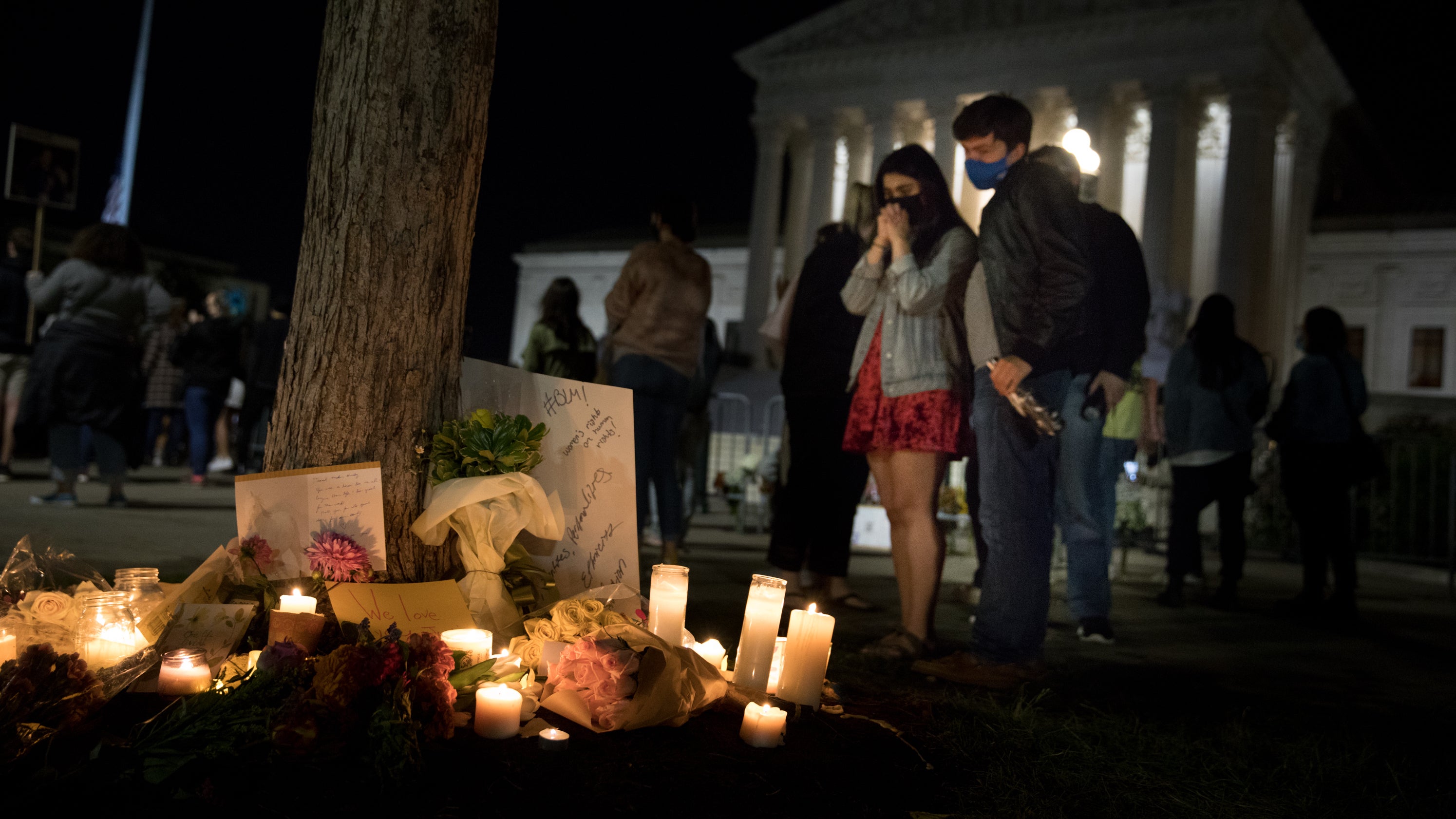 Makek Ahmad (left) and Jack Korologos(right) stop to look at the candles, signs and flowers left in front of the U.S. Supreme Court.