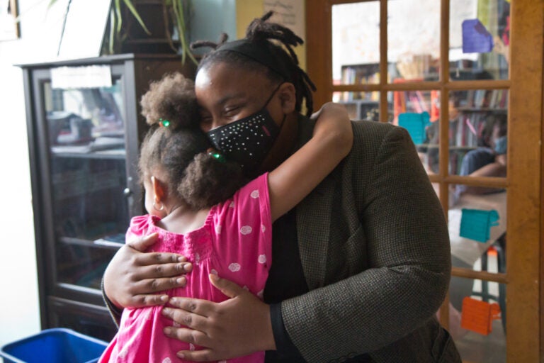 Tree House Books program director Sabriaya Shipley hugs Ayah Robinson, 8. (Kimberly Paynter/WHYY)