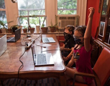 Two kids at kitchen table, wearing masks during virtual learning
