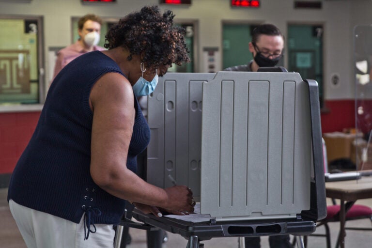 The first voter at the Liacouras Center satellite election office, Priscilla Bennett, fills out her official mail-in ballot, and demonstrates for the press the process. (Kimberly Paynter/WHYY)