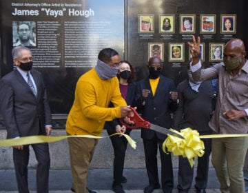 James “Yaya” Hough, first-ever artist-in-residence at the Philadelphia District Attorney’s Office, cuts a ribbon with DA Larry Krasner (left), Mural Arts' Jane Golden, (third from left), Michael “Smokey” Wilson, (third from right) and boxing champion Bernard Hopkins (right). (Kimberly Paynter/WHYY)