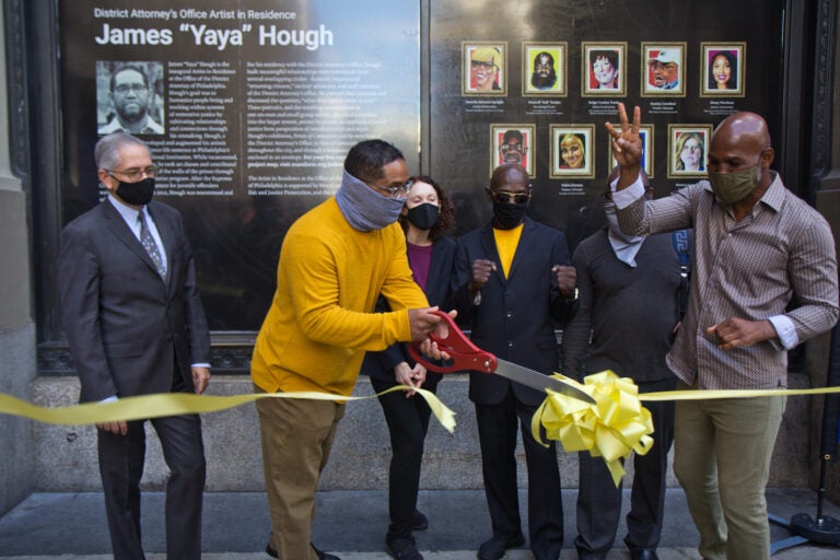James “Yaya” Hough, first-ever artist-in-residence at the Philadelphia District Attorney’s Office, cuts a ribbon with DA Larry Krasner (left), Mural Arts' Jane Golden, (third from left), Michael “Smokey” Wilson, (third from right) and boxing champion Bernard Hopkins (right). (Kimberly Paynter/WHYY)