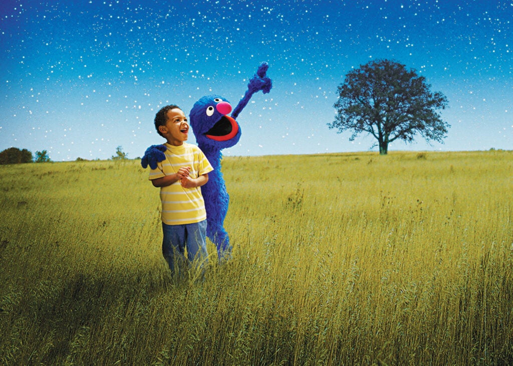 A child with Elmo under a starry night sky