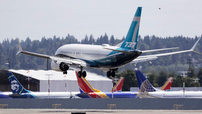 A Boeing 737 Max heads to a landing past grounded Max jets at Seattle’s Boeing Field, following a test flight in June. It was the first of three days of re-certification test flights that mark a step toward returning the aircraft to passenger service.