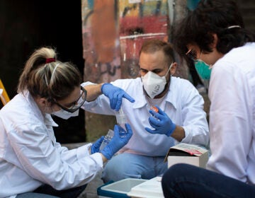 Researchers of the Rio de Janeiro State University prepare an instrument to sample airborne sewage droplets for the presence of the new coronavirus at the Santa Marta slum, in Rio de Janeiro, Brazil, Monday, July 27, 2020. The researchers are working together with volunteers of a local sanitation team to see if they can detect the virus in the air and evaporation from the slum’s open-air sewers. (AP Photo/Silvia Izquierdo)