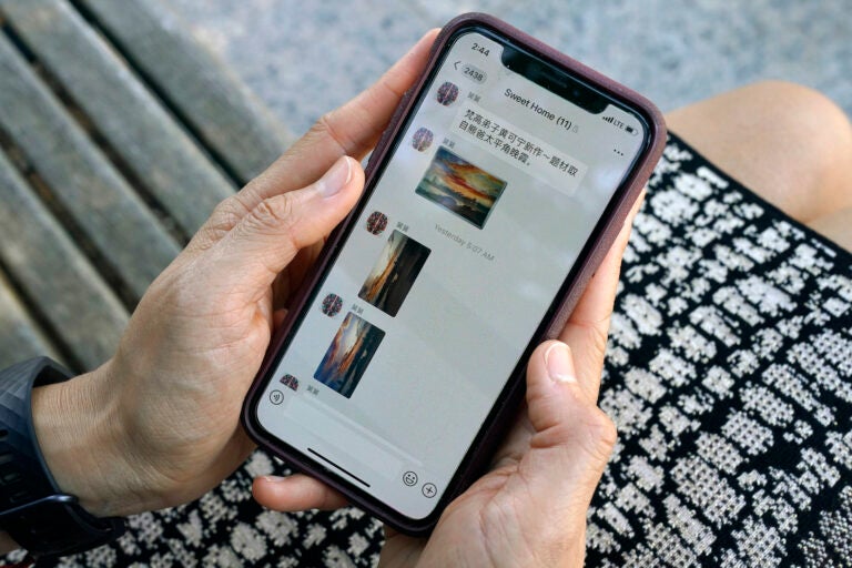 Sha Zhu, of Washington, shows the app WeChat on her phone, which she uses to keep in touch with family and friends in the U.S. and China, Tuesday Aug. 18, 2020, in Washington. (AP Photo/Jacquelyn Martin)