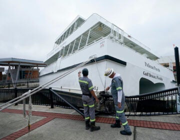 Workers look over a damaged ferry, Thursday, Sept. 17, 2020, in Pensacola, Fla. (AP Photo/Gerald Herbert)