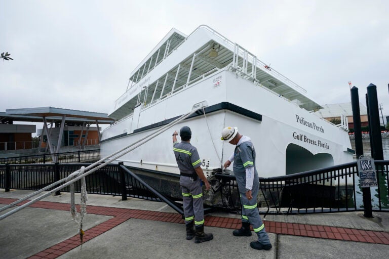 Workers look over a damaged ferry, Thursday, Sept. 17, 2020, in Pensacola, Fla. (AP Photo/Gerald Herbert)