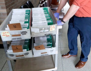 In this May 5, 2020, file photo, absentee ballots to be counted are moved at City Hall in Garden City, Mich. (AP Photo/Paul Sancya, File)