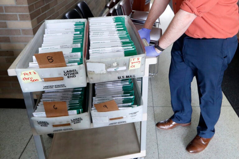 In this May 5, 2020, file photo, absentee ballots to be counted are moved at City Hall in Garden City, Mich. (AP Photo/Paul Sancya, File)