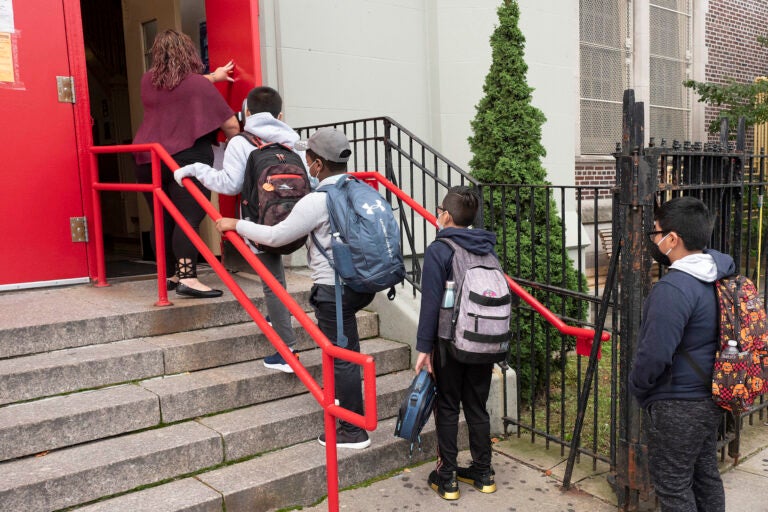 A teacher leads her students into PS 179 elementary school