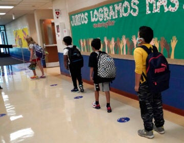 Students physically distance as they walk to their classroom