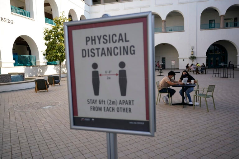 People sit at tables at San Diego State University Wednesday, Sept. 2, 2020, in San Diego. San Diego State University on Wednesday halted in-person classes for a month after dozens of students were infected with the coronavirus. (AP Photo/Gregory Bull)