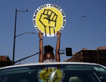 In this July 20, 2020, file photo, Audrey Reed, 8, holds up a sing through the sunroof of a car during a rally in Los Angeles. Ahead of Labor Day, major U.S. labor unions say they are considering work stoppages in support of the Black Lives Matter movement. (AP Photo/Jae C. Hong)