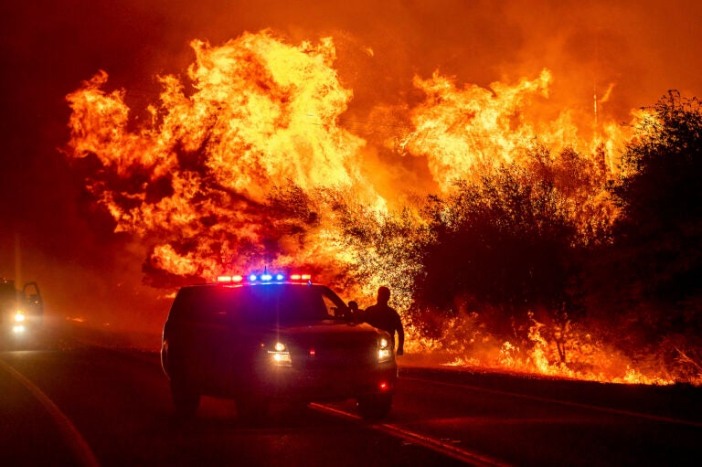 Flames lick above vehicles on Highway 162 as the Bear Fire burns in Oroville, Calif.