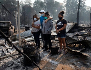 The Reyes family looks at the destruction of their trailer at the Coleman Creek Estates where 121 trailers burned as wild fires devastate the region on Thursday in Portland, Ore. The Reyes family lived in the park for 20 years. (AP Photo/Paula Bronstein)