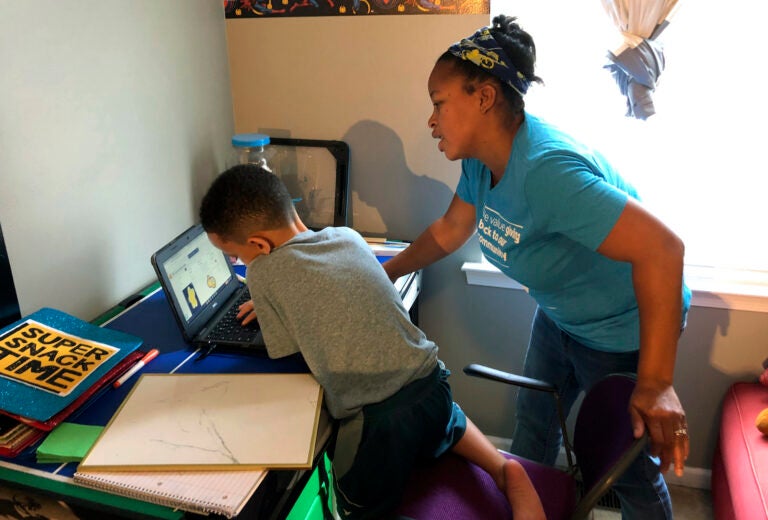 Tiffany Shelton helps her 7-year-old son, P.J. Shelton, a second-grader, during an online class at their home in Norristown, Pa., on Thursday, Sept. 3, 2020. (AP Photo/Michael Rubinkam)