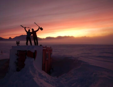 In this handout photo provided by British Antarctic Survey, field guides Sarah Crowsley, left, and Sam Hunt, right, pose for a photo after digging out the caboose, a container used for accommodation that can be moved by a tractor, at Adelaide island, in Antarctica on Friday, June 19, 2020. (Robert Taylor/British Antarctic Survey via AP)