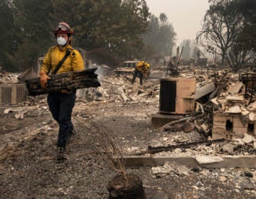 Jackson County District 5 firefighter Captain Aaron Bustard works on a smoldering fire in a burned neighborhood in Talent, Ore., Friday, Sept. 11, 2020, as destructive wildfires devastate the region. (AP Photo/Paula Bronstein)