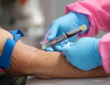 A health worker draws blood from a patient