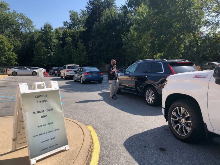 EastSide Charter principal Aaron Bass talks to a driver waiting in line at Walgreens. (Cris Barrish/WHYY)