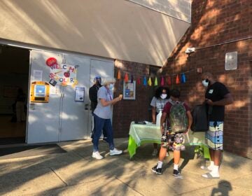 Tammy Harrity and other Simpson Recreation Center staffers greet Kyree Robinson and his son Syire. (Emily Rizzo for WHYY)