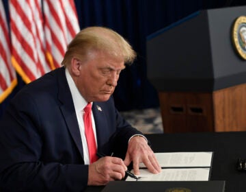 President Trump signs one of four executive orders addressing the economic fallout from the pandemic in Bedminster, N.J., on Aug. 8. The Trump administration has given employers the option to stop collecting payroll taxes, but workers may have to repay the money next year.