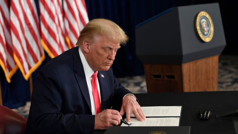 President Trump signs one of four executive orders addressing the economic fallout from the pandemic in Bedminster, N.J., on Aug. 8. The Trump administration has given employers the option to stop collecting payroll taxes, but workers may have to repay the money next year.
