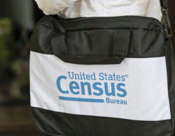 A U.S. Census Bureau worker carries a briefcase while knocking on the door of a home in August in Winter Park, Fla. (John Raoux/AP)