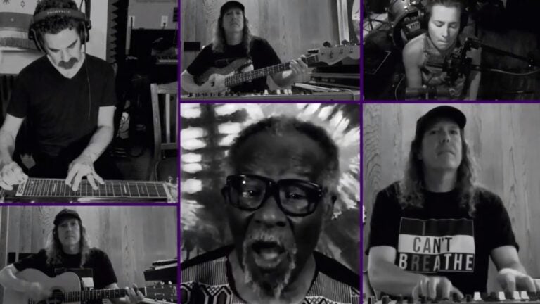 A black and white screenshot of musicians performing a song virtually through Zoom