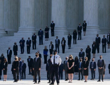 Former law clerks for Justice Ruth Bader Ginsburg stand on the steps of the Supreme Court as they await the arrival of the casket of Ginsburg on Wednesday. (Claire Harbage/NPR)