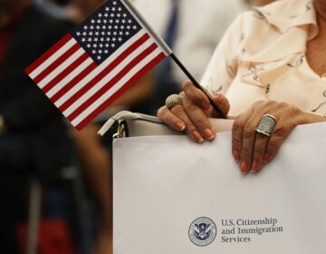 An attendee holds an American flag at a U.S. Citizenship & Immigration Services naturalization ceremony