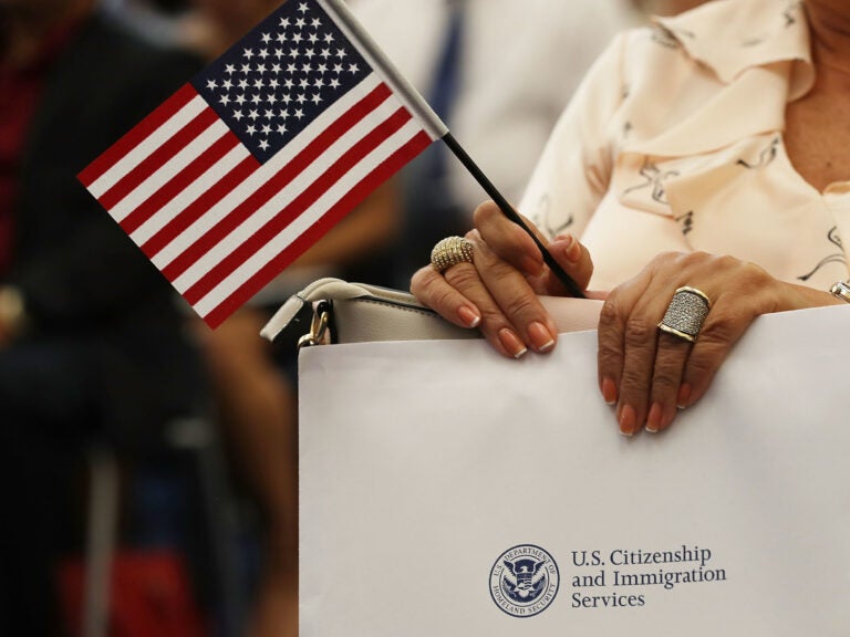 An attendee holds an American flag at a U.S. Citizenship & Immigration Services naturalization ceremony