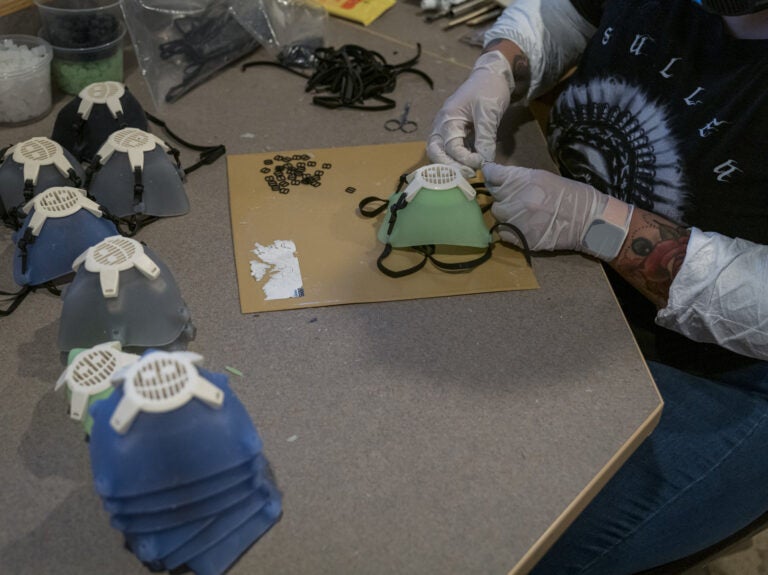 A worker wearing protective gloves attaches an elastic strap to a silicone face mask at Mask & Shield, a division of Monster City Studios, in Fresno, California, U.S., on Wednesday, May 27, 2020. Monster City Studios, a company that normally makes amusement park and movie props, has pivoted to manufacturing MCS face shields with forehead protection. Photographer: David Paul Morris/Bloomberg via Getty Images