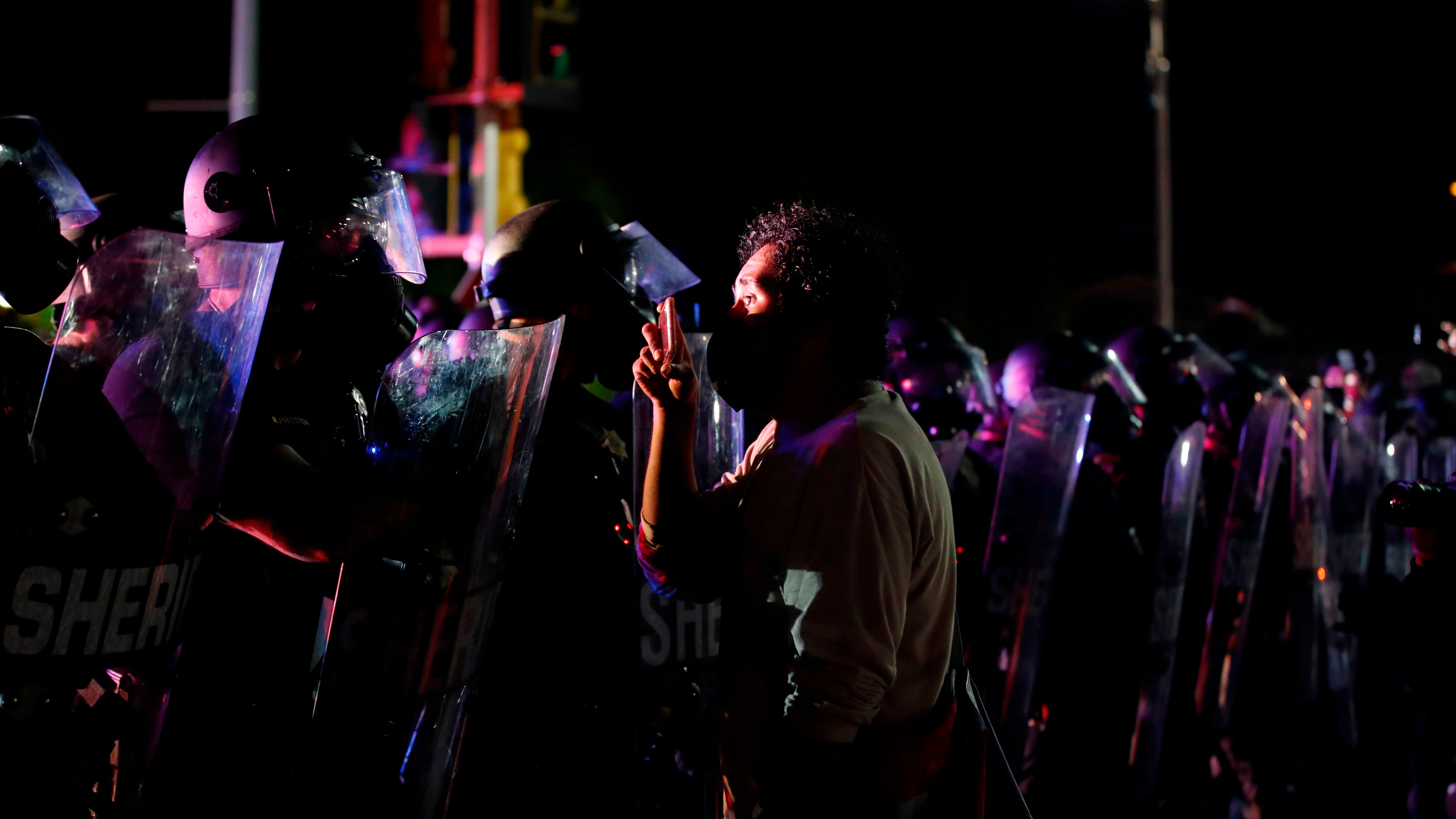 A protester stands face to face with police during demonstrations against the shooting of Jacob Blake in Kenosha, Wis., on August 25, 2020.