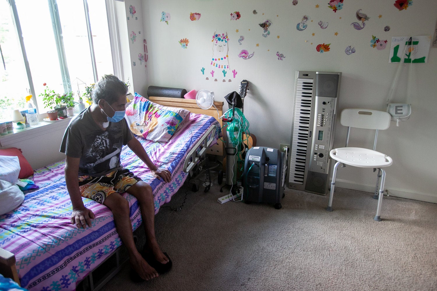 Jose sits on the edge of his bed at his home