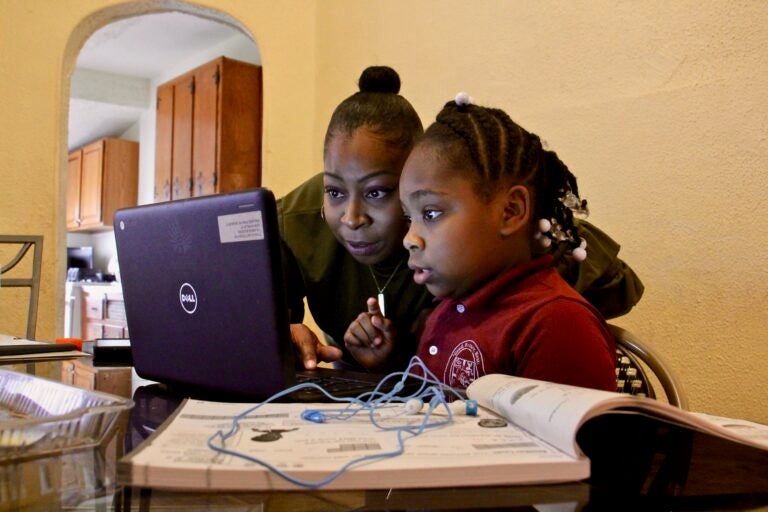 Yolanda Biggers helps her daughter, Zyiah Satterwhite, 7, find her assignment.