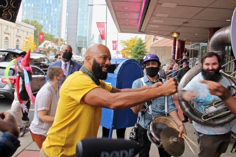 Common, the rapper also known as Lonnie Rashid Lynn, bumps fists with members of the Snack Time Band outside the Liacouras Center after an impromptu jam session. (Emma Lee/WHYY)