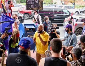 Common jams with the Snacktime Band outside the Liacouras Center, a surprise addition to the Cirque d'Vote entertainment for voters waiting in line there. (Emma Lee/WHYY)