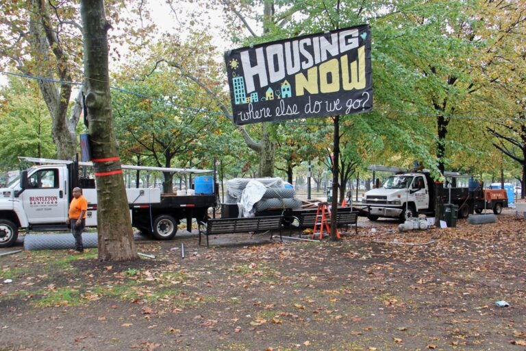 Workers put up fences around the Von Colln Field as the homeless encampment there is disassembled. (Emma Lee/WHYY)