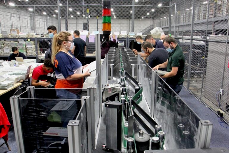 Election workers operate a sorting machine at Camden County Elections and Archive Center