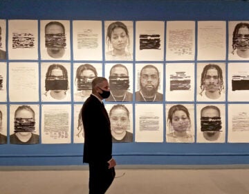 District Attorney Larry Krasner views 'Redaction,' a mural of portraits by Titus Kaphar and Reginald Dwayne Betts in the gallery of the African American Museum of Philadelphia